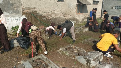 Warga dan Muspika Pamarican membersihkan makam pahlawan pada peringatan HUT Bhayangkara